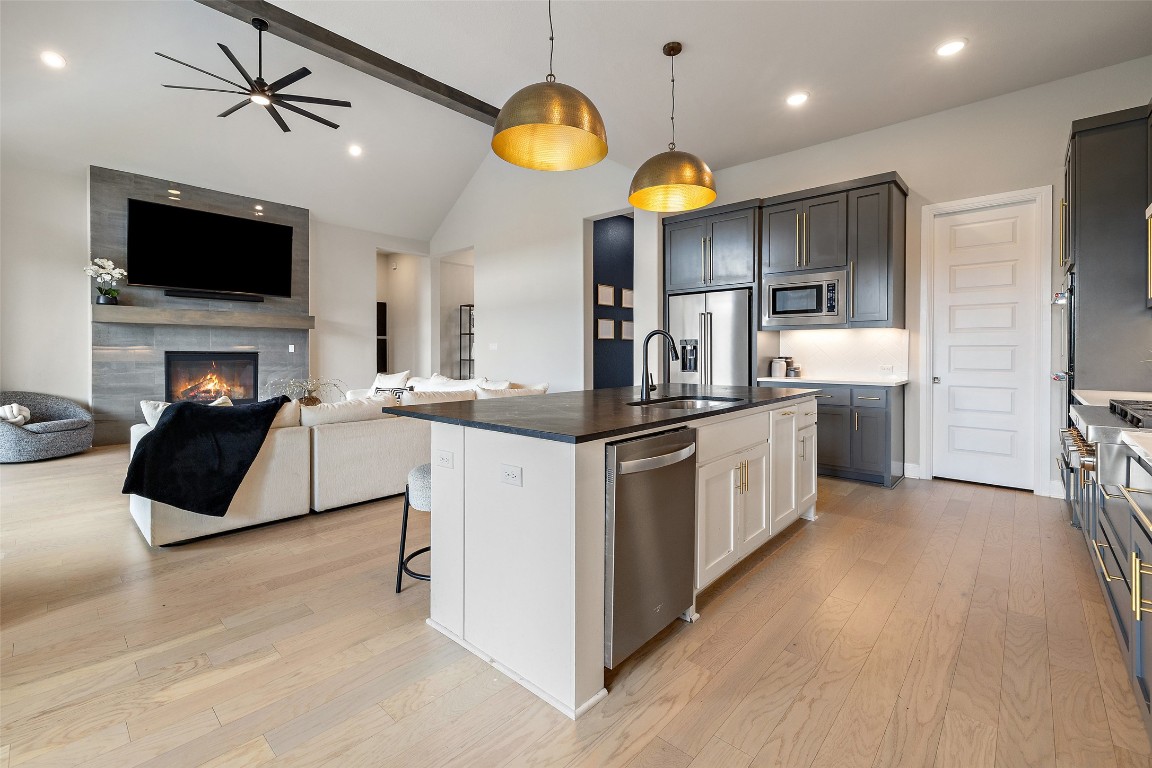 2220 Normandy View Leander, TX 78641 - Photo 40 of 40 Kitchen with a breakfast bar, open floor plan, light wood-style flooring, a kitchen island with sink, and hanging light fixtures