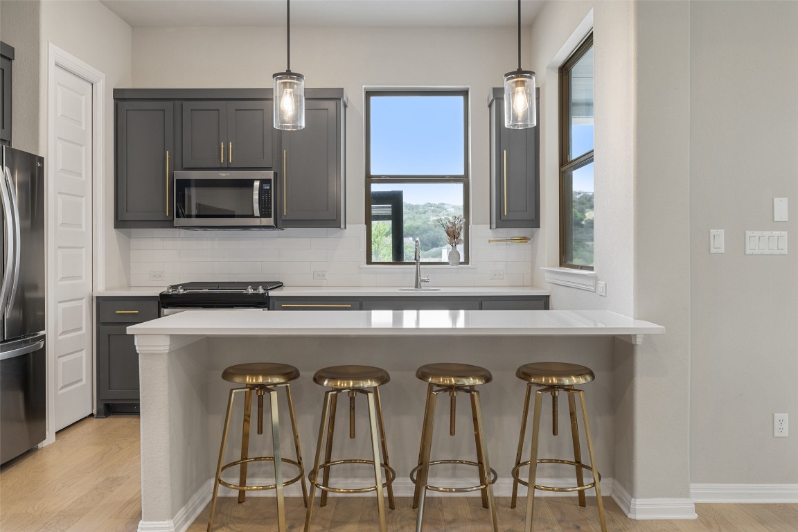2220 Normandy View Leander, TX 78641 - Photo 34 of 40 Kitchen featuring a kitchen breakfast bar, backsplash, stainless steel appliances, and pendant lighting