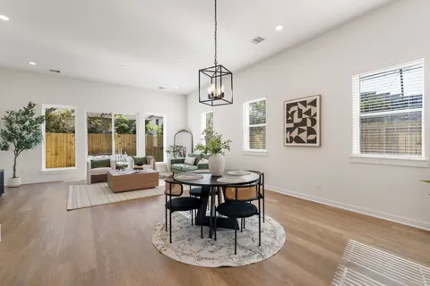 a dining room with wooden floor a chandelier a glass table and chairs