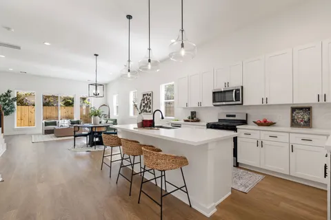 a kitchen with stainless steel appliances kitchen island granite countertop a stove a sink a dining table and chairs with wooden floor