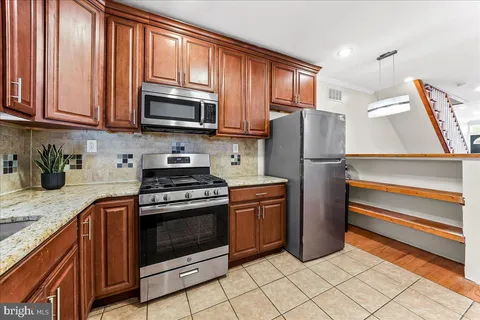 a kitchen with granite countertop wooden cabinets stainless steel appliances and a window