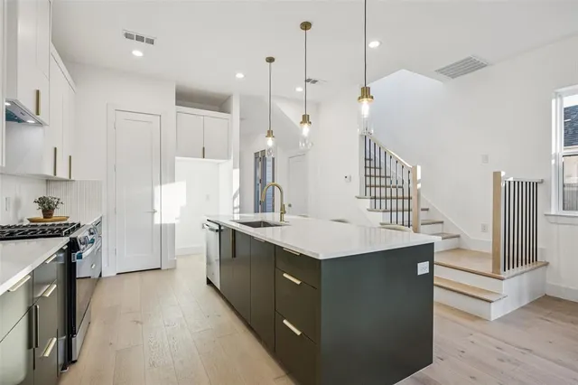 a kitchen with granite countertop a sink a counter top space stainless steel appliances and cabinets