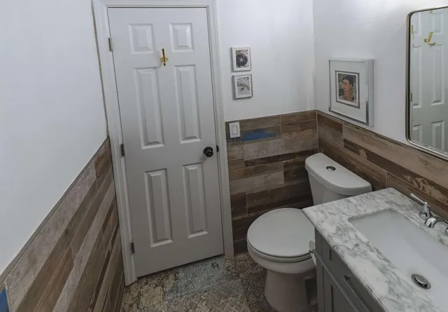 a bathroom with a granite countertop toilet and a sink