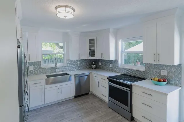 a kitchen with cabinets appliances a sink and a window