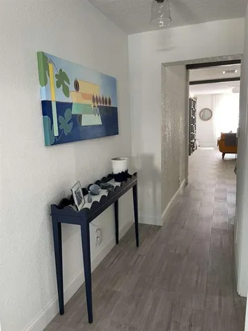 a view of a hallway to room with wooden floor and furniture
