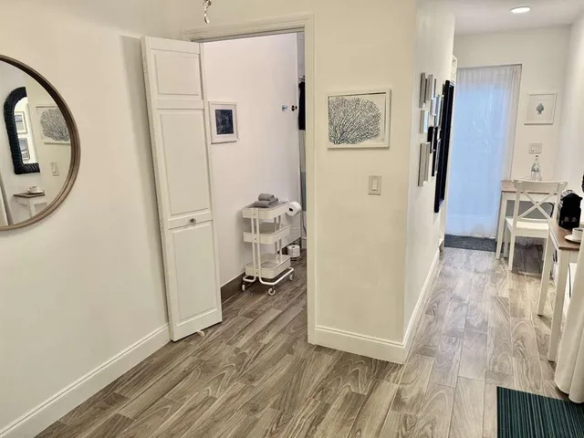 a view of a hallway with wooden floor and a livingroom