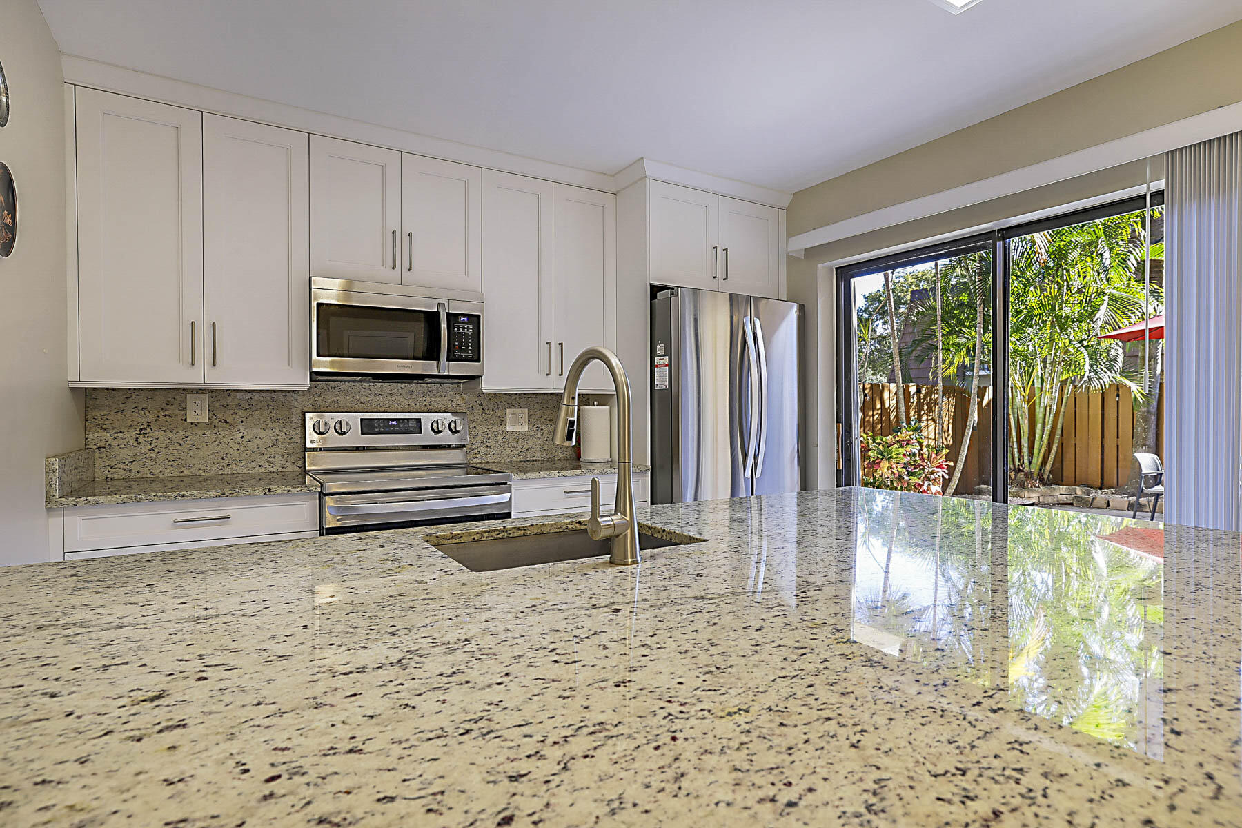 3071 30th Court Jupiter, FL 33477 - Photo 16 of 51 a view of kitchen with granite countertop a stove top oven a sink and a refrigerator