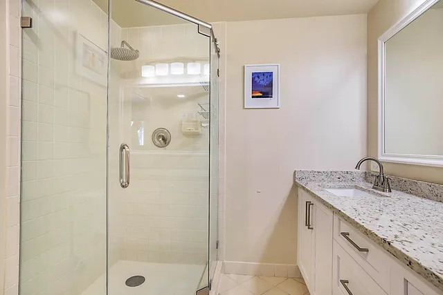 a bathroom with a granite countertop shower sink vanity and mirror