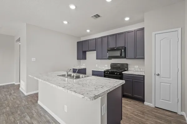 a kitchen with kitchen island granite countertop a sink stove and refrigerator