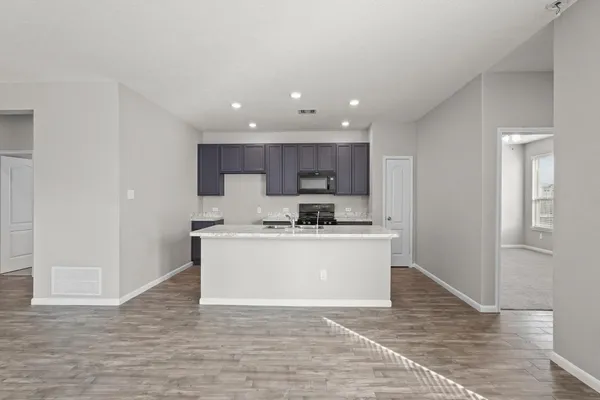 a view of kitchen with granite countertop refrigerator stove top oven and cabinets