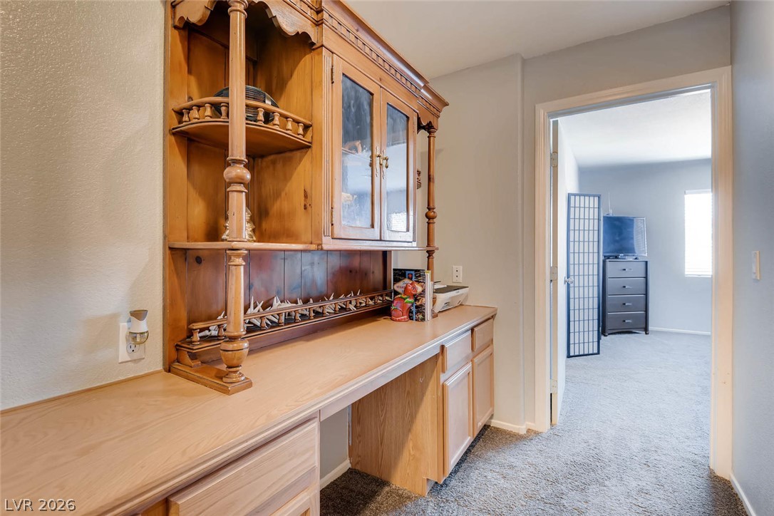 10451 Processor Court Las Vegas, NV 89129 - Photo 23 of 28 A built-in wooden desk with upper cabinetry offers a dedicated workspace within a functional layout.