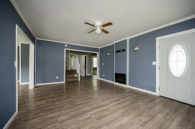 a view of an empty room with wooden floor and a window