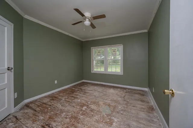 an empty room with ceiling fan and window