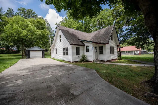 a view of a yard in front of a house with plants and large tree