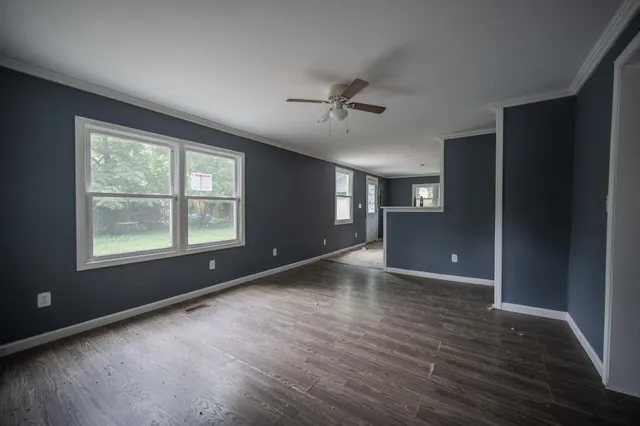a view of an empty room with a window and wooden floor
