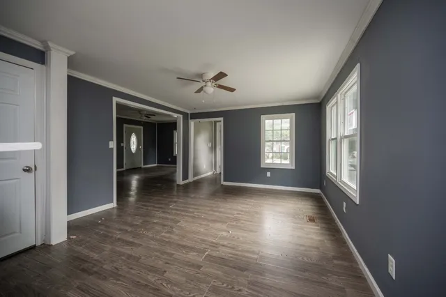 a view of an empty room with window and wooden floor