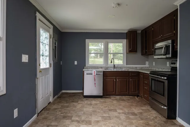 a kitchen with stainless steel appliances granite countertop a stove a sink and a microwave