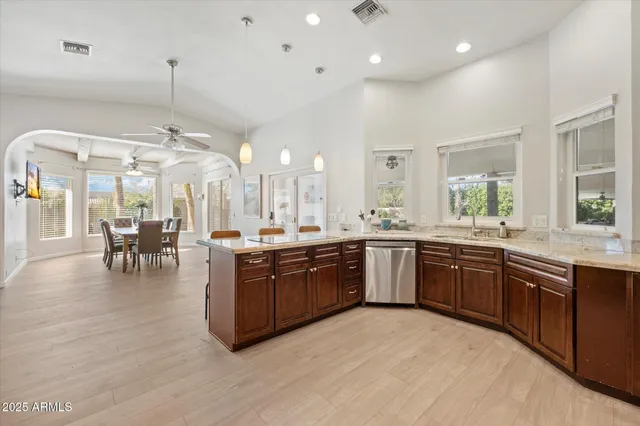 a large kitchen with a large counter top space a sink stainless steel appliances and windows