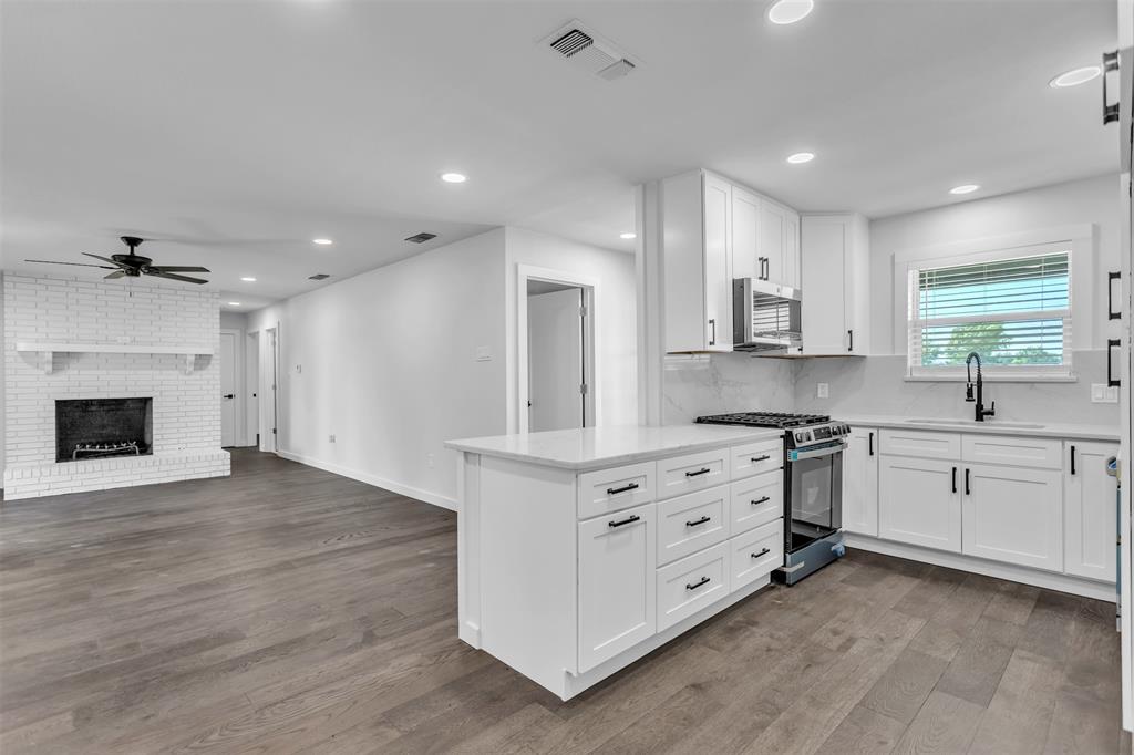 a kitchen with stainless steel appliances white cabinets and a fireplace