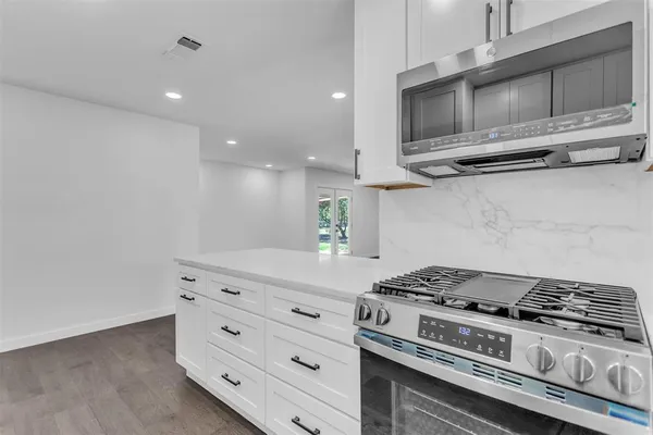 a kitchen with granite countertop a stove and a microwave