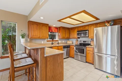 a kitchen with stainless steel appliances granite countertop a refrigerator stove and a sink