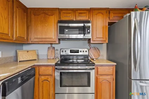 a kitchen with stainless steel appliances granite countertop a refrigerator and a stove top oven