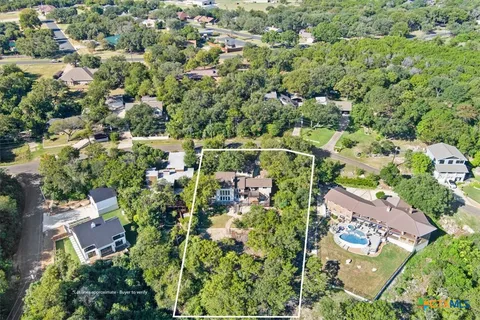 an aerial view of residential houses with outdoor space and trees
