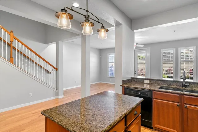 a kitchen with stainless steel appliances granite countertop a sink a stove and a wooden cabinets