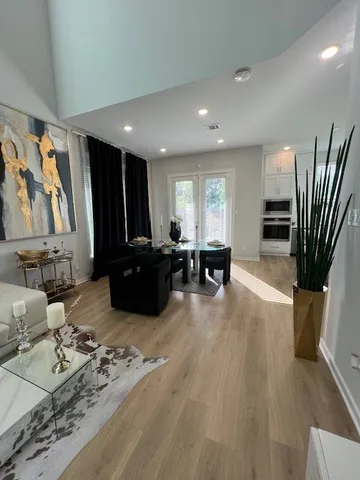 a kitchen with stainless steel appliances granite countertop a stove a sink dishwasher a refrigerator and white cabinets with wooden floor