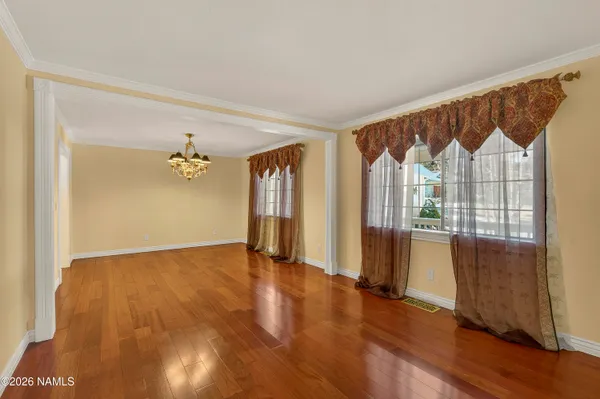 a view of an empty room with window and chandelier fan