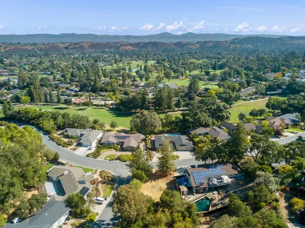 an aerial view of residential houses with outdoor space and trees
