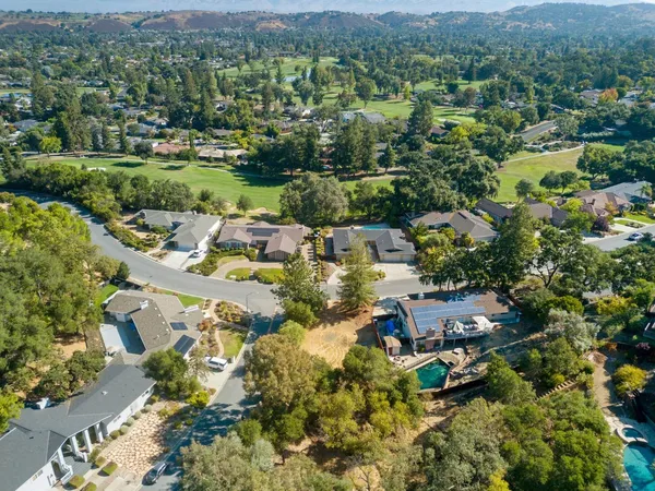 an aerial view of residential houses with outdoor space and trees