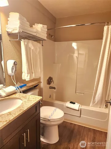a bathroom with a granite countertop bathtub sink vanity mirror and toilet
