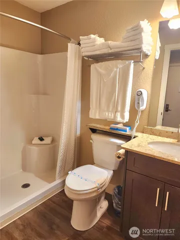 a bathroom with a granite countertop sink a toilet and shower