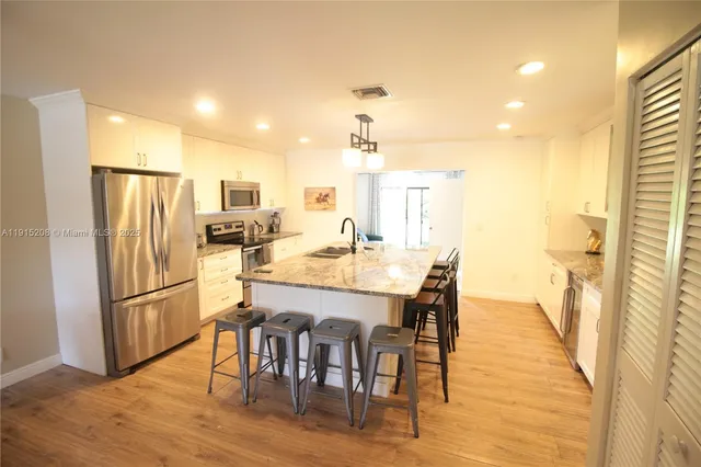 a kitchen with stainless steel appliances a dining table chairs and refrigerator