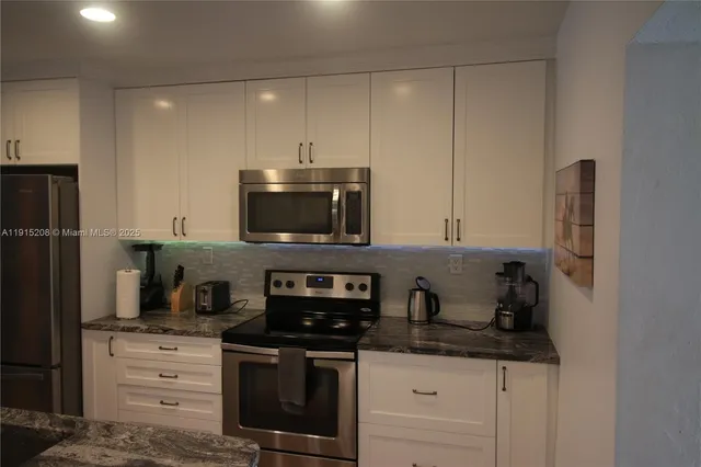a kitchen with stainless steel appliances granite countertop a sink stove and refrigerator