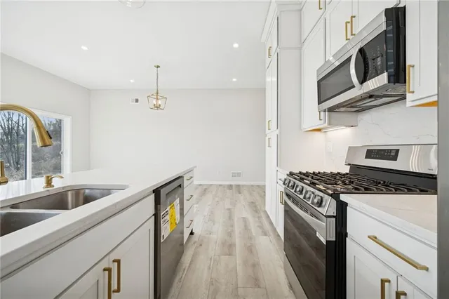 a kitchen with stainless steel appliances granite countertop a sink and a stove