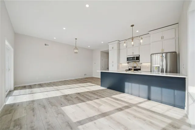 a large white kitchen with kitchen island white cabinets and refrigerator