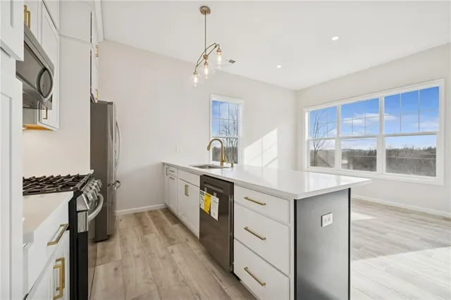 a kitchen with a sink appliances wooden floor and cabinets