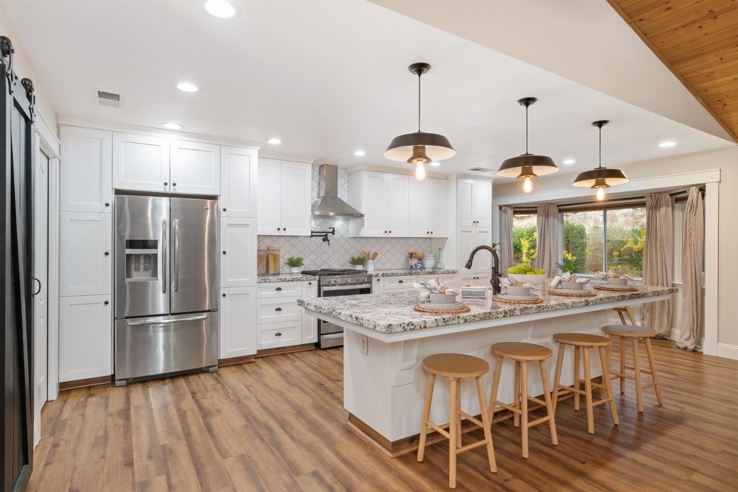 25390 White Thorne Road Clovis, CA 93619 - Photo 17 of 50 a kitchen with stainless steel appliances granite countertop a refrigerator a sink dishwasher a stove and white cabinets with wooden floor