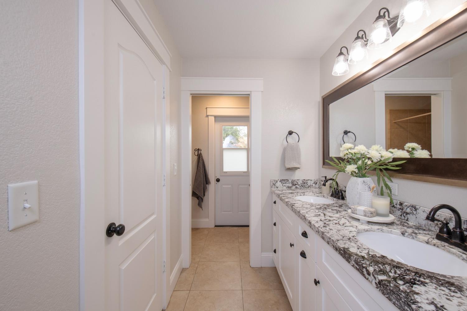 25390 White Thorne Road Clovis, CA 93619 - Photo 27 of 50 a bathroom with a granite countertop sink a mirror and shower