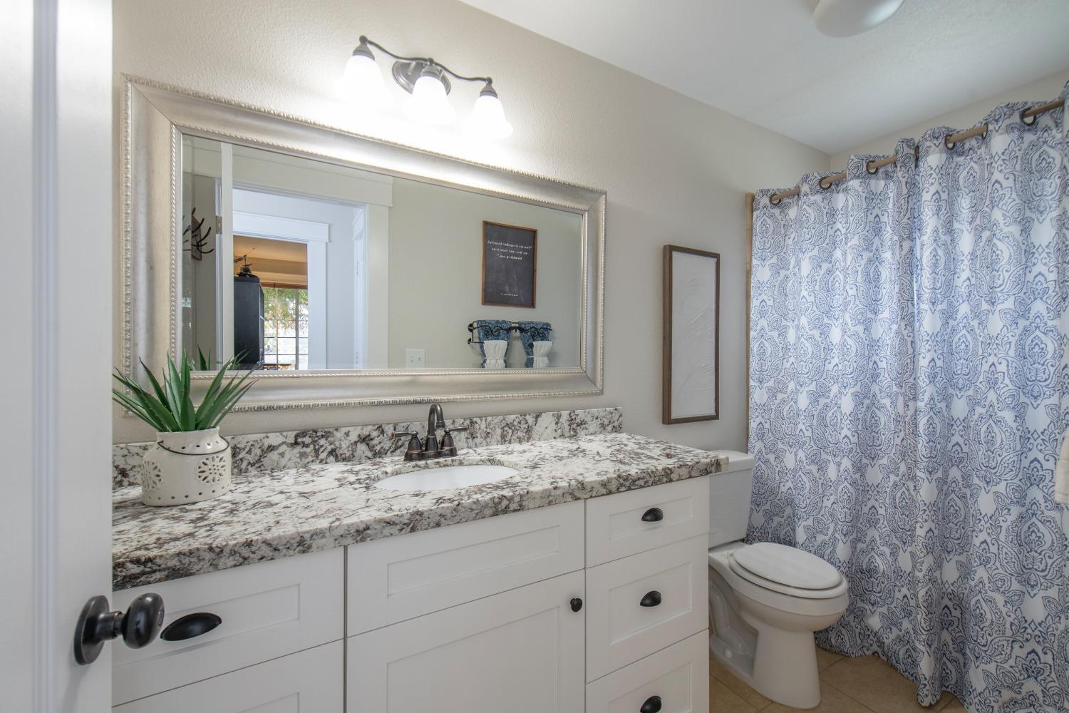 25390 White Thorne Road Clovis, CA 93619 - Photo 30 of 50 a bathroom with a granite countertop sink a toilet and mirror