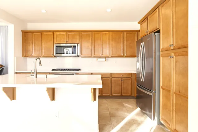 a kitchen with stainless steel appliances granite countertop a refrigerator a stove and a sink with wooden floor