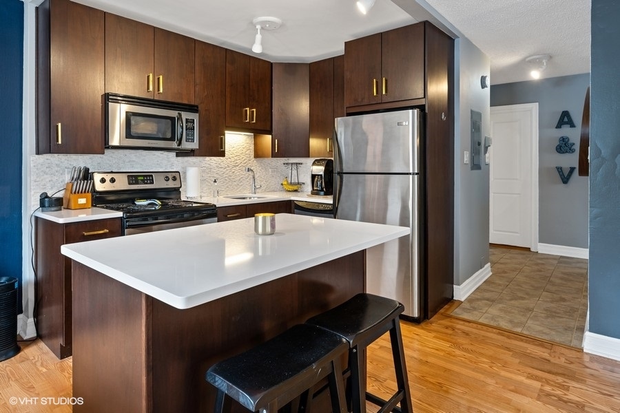 2930 North Sheridan Road, Unit 312 Chicago, IL 60657 - Photo 6 of 14 a kitchen with stainless steel appliances a refrigerator a stove a microwave a sink and cabinets