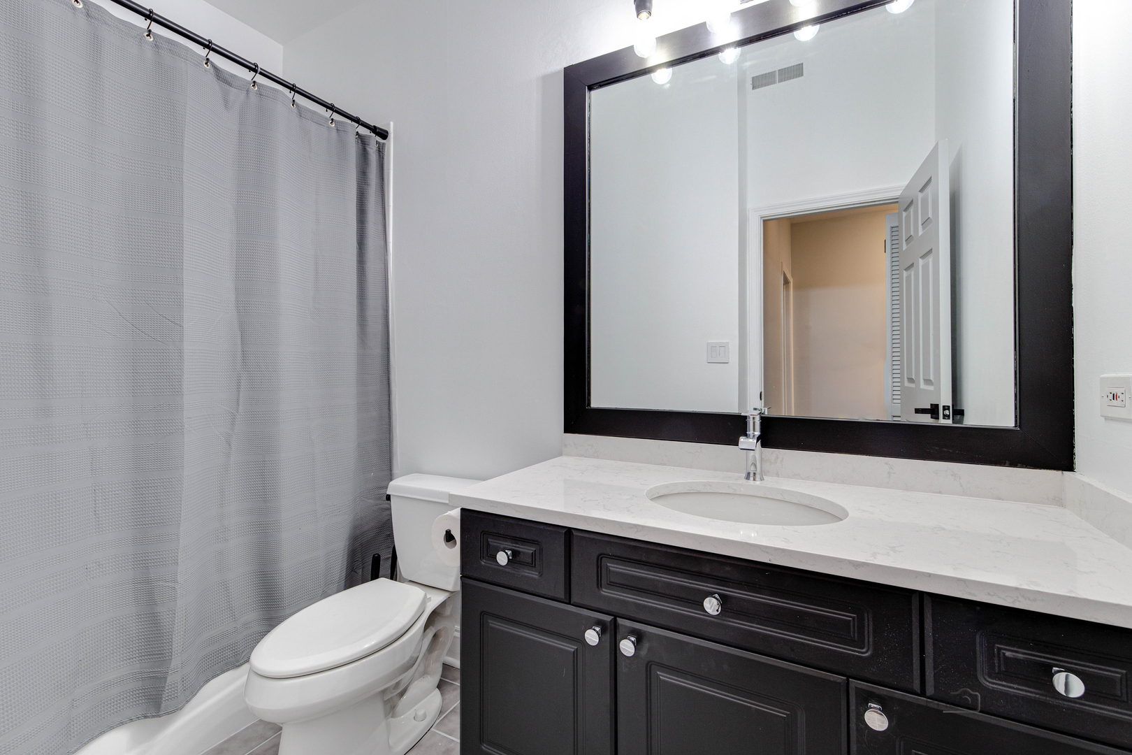 1301 West Washington Boulevard, Unit 309 Chicago, IL 60607 - Photo 22 of 23 a bathroom with a sink a toilet a mirror and shower curtain