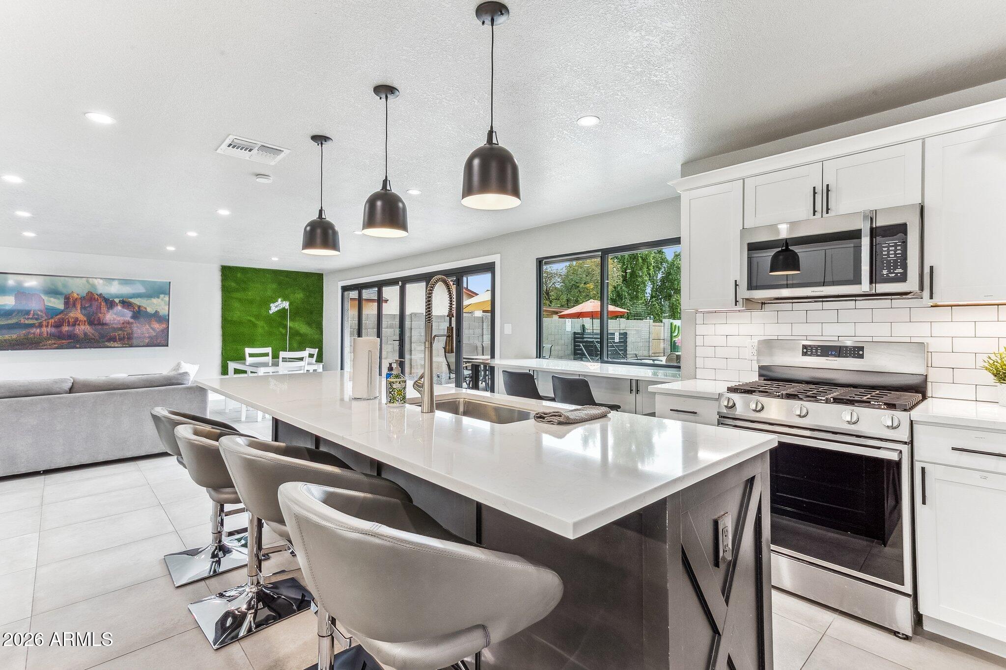 8725 East Osborn Road Scottsdale, AZ 85251 - Photo 11 of 33 a kitchen with stainless steel appliances a dining table chairs stove refrigerator and microwave