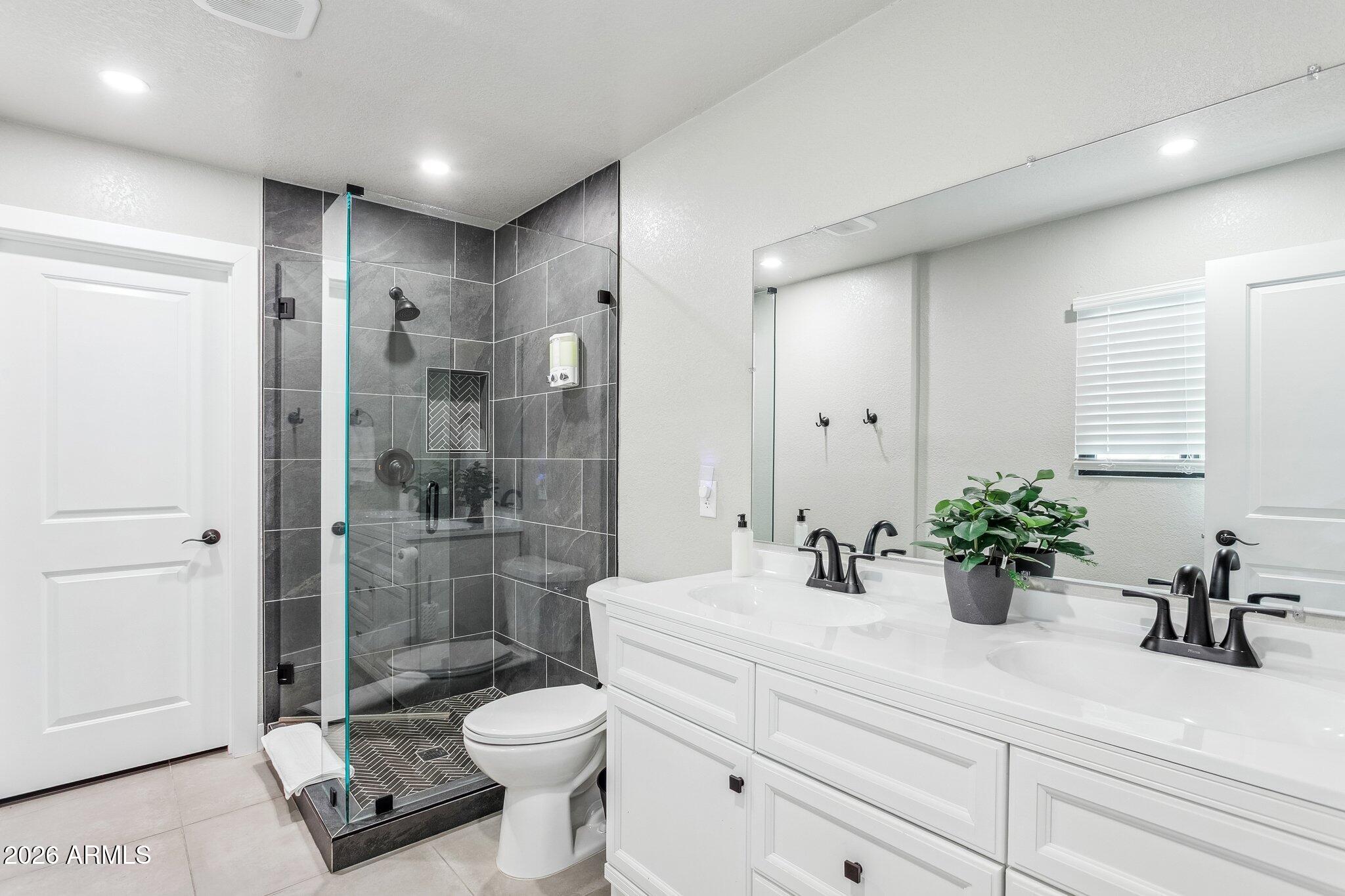 8725 East Osborn Road Scottsdale, AZ 85251 - Photo 14 of 33 a bathroom with a sink a toilet a glass door a shower and a mirror