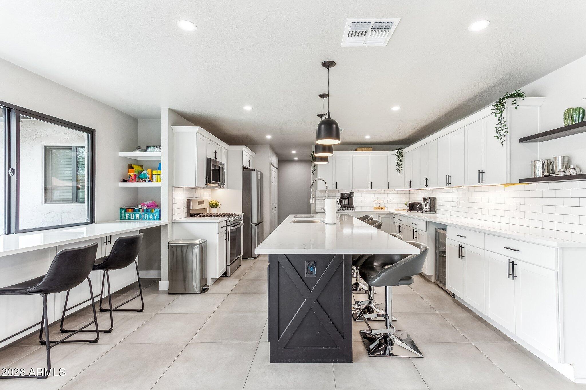 8725 East Osborn Road Scottsdale, AZ 85251 - Photo 3 of 33 a kitchen with stainless steel appliances kitchen island granite countertop a table chairs sink and cabinets