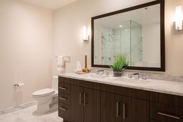 a bathroom with a double vanity sink toilet and mirror