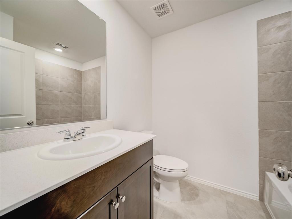357 Sun Bluff Road Fort Worth, TX 76052 - Photo 13 of 35 Bathroom featuring a dark wood-finish vanity with a white countertop and integrated sink, a large wall-mounted mirror, and a white toilet